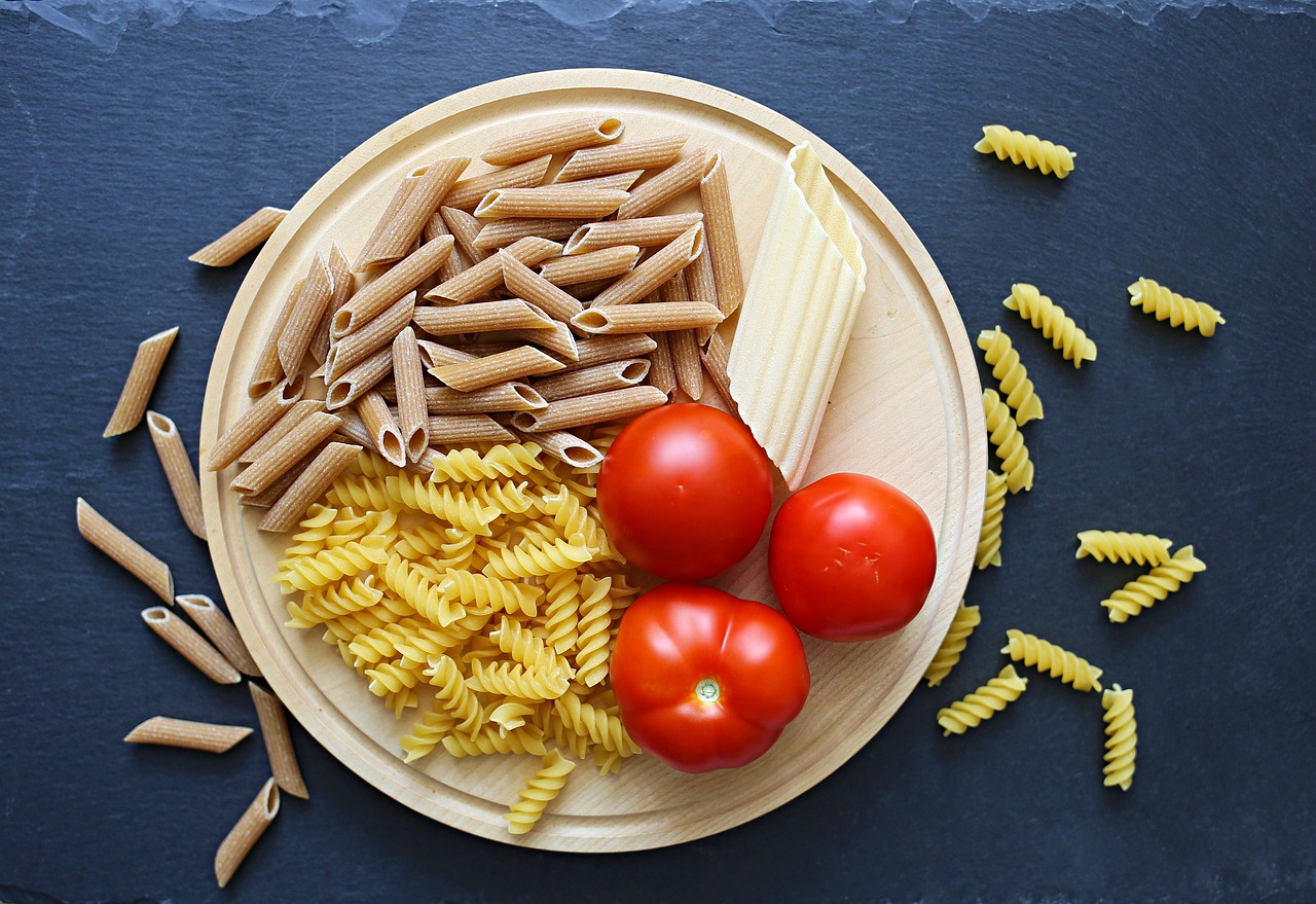 A colorful bowl of macaroni salad topped with fresh vegetables and herbs