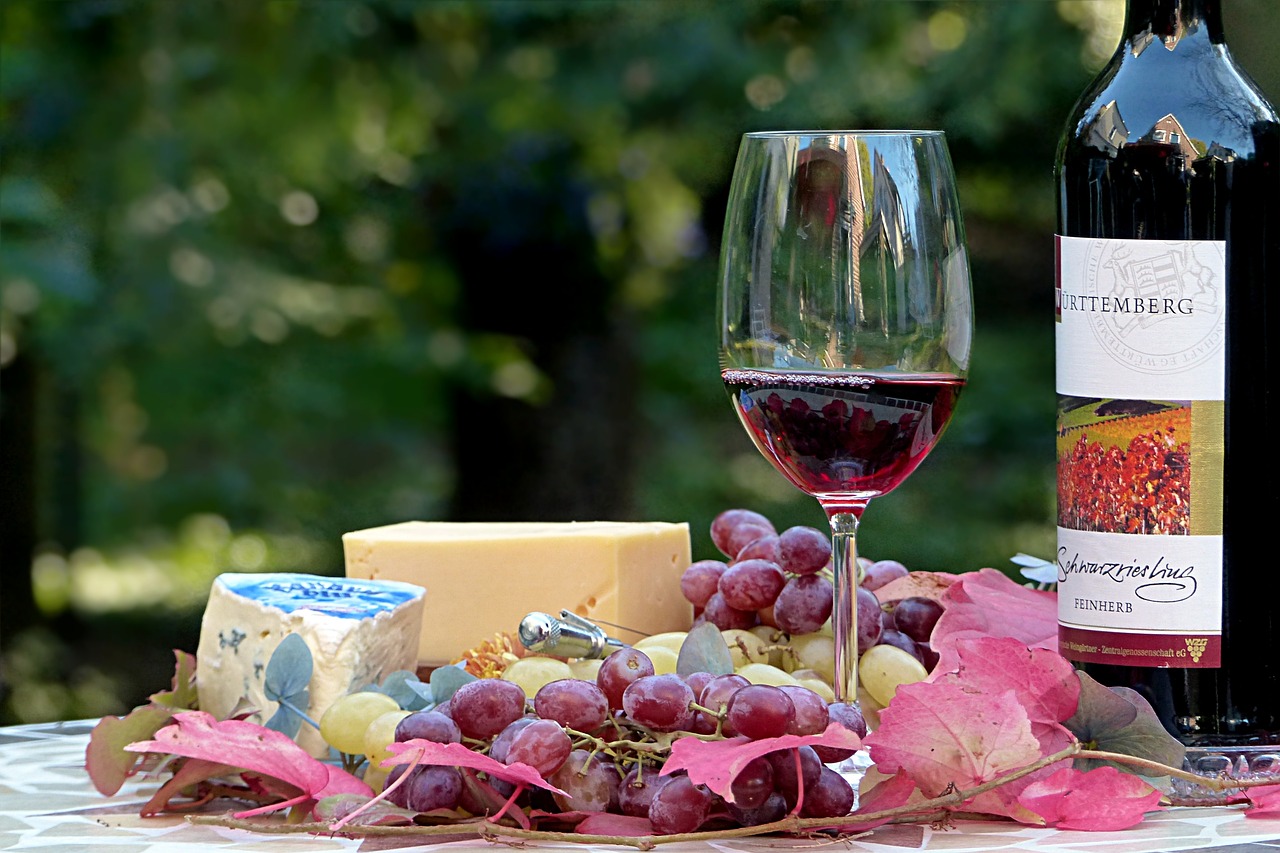 Artistic wine and cheese pairing on a wooden board with fruits and wine glasses.